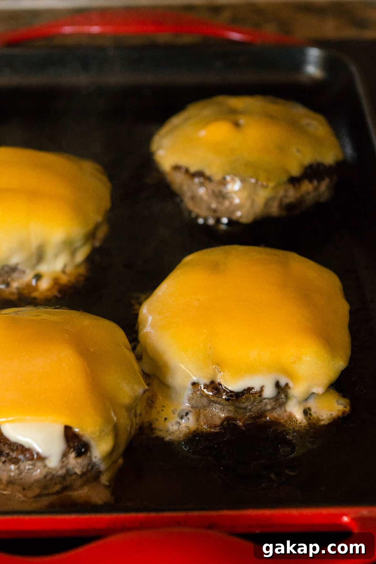 burger patties with melted cheese on griddle