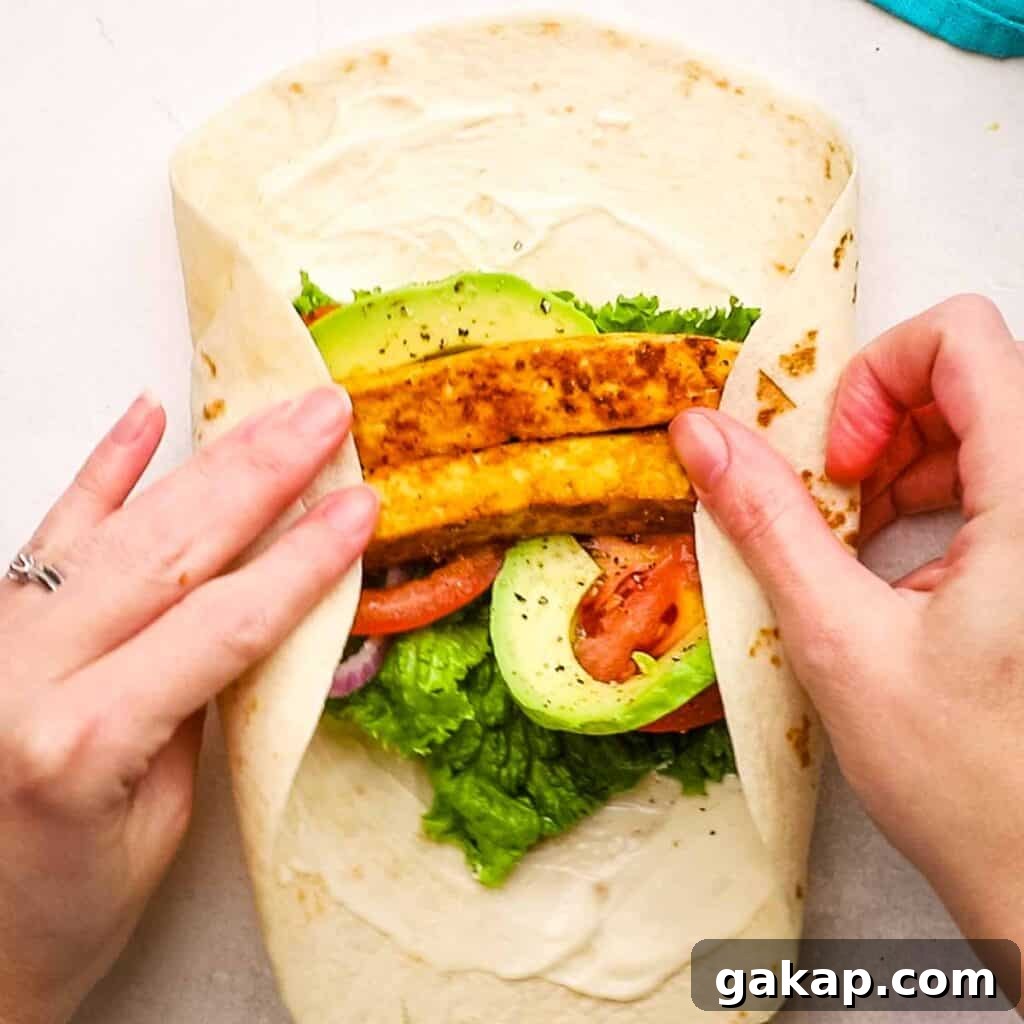 Folding a tortilla wrap filled with ingredients.