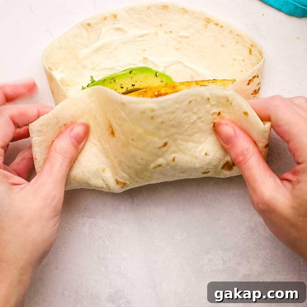 Pressing one side of the tortilla to the center with the filling.
