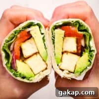 two hands holding and showing the inside of a tofu wrap