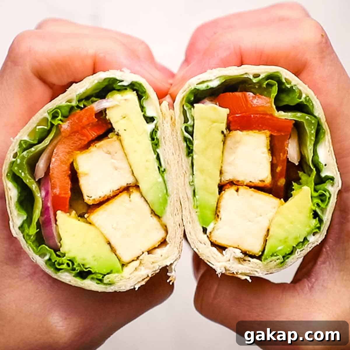 two hands holding and showing the inside of a tofu wrap