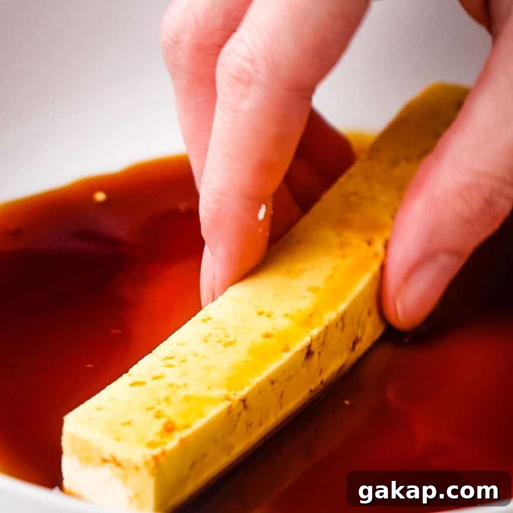 Dipping tofu stick into the tamari.