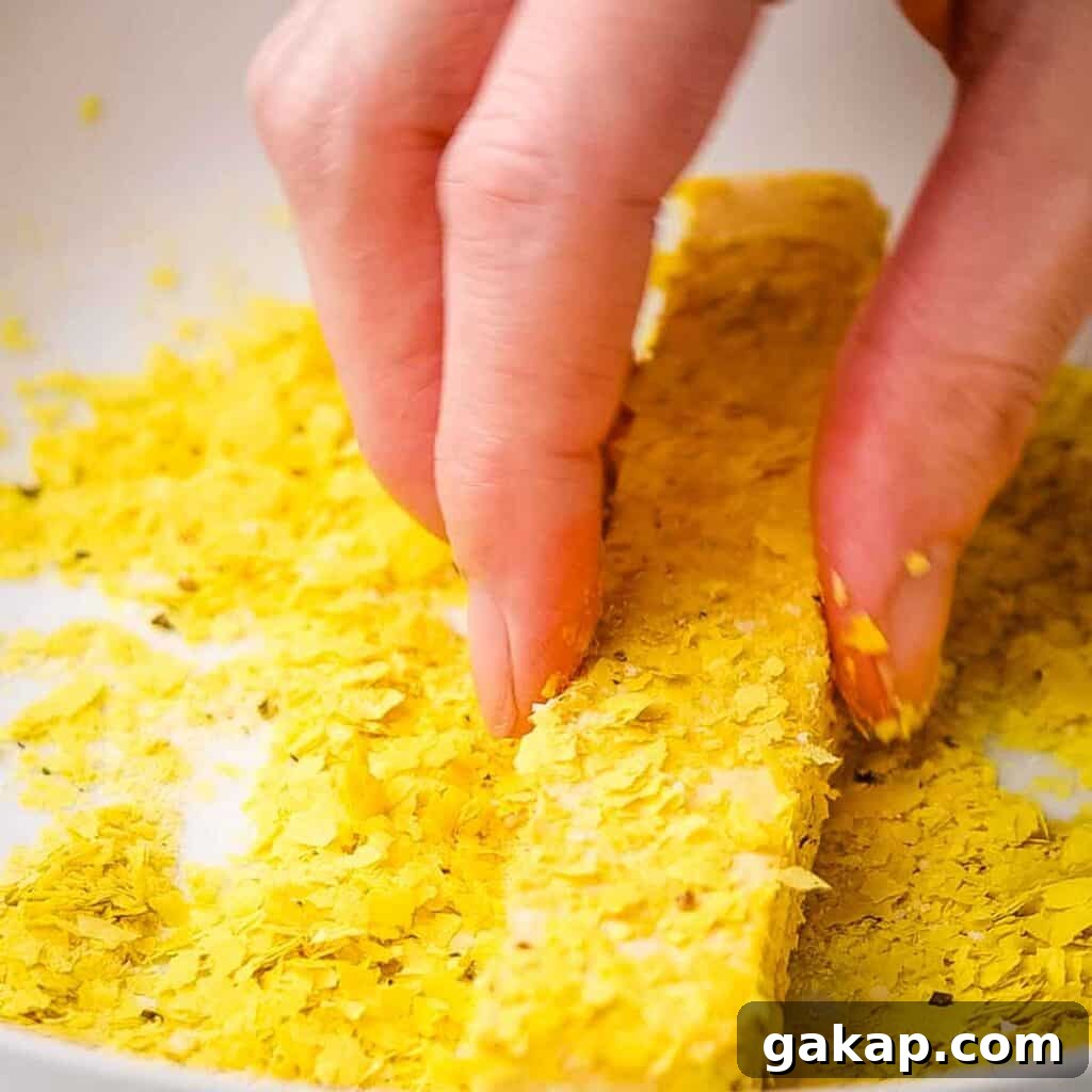 Coating tofu sticks in the nutritional yeast mixture.