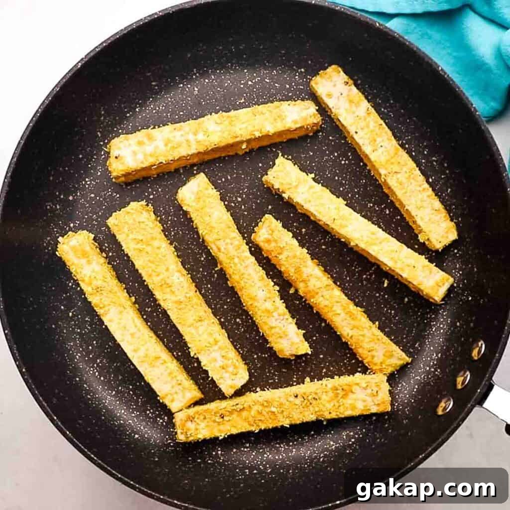 Pan frying the coated tofu sticks.
