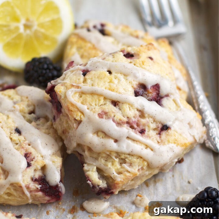 blackberry lemon scone with fresh lemon glaze on a baking sheet with lemons and blackberries