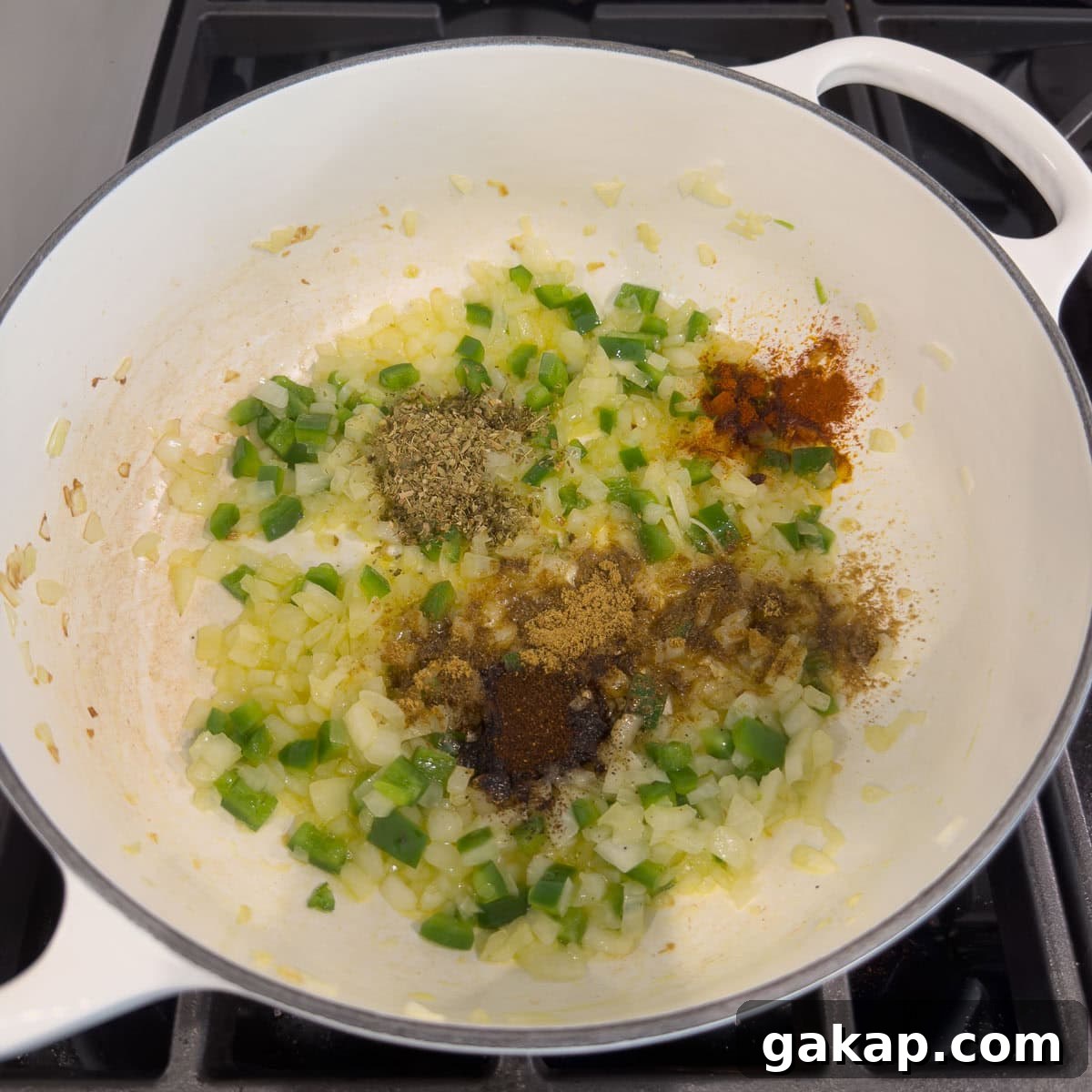 Spices, herbs, onion, and jalapeno cooking in olive oil