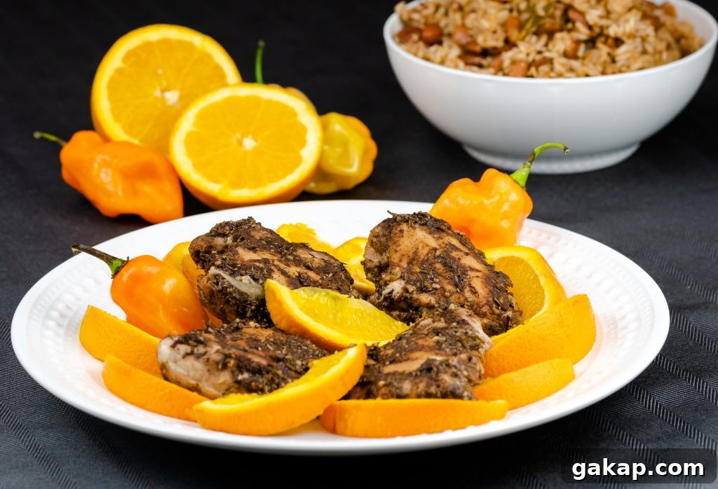 Instant Pot Jamaican Jerk chicken served on a platter with orange slices and hot peppers served with a side of rice.